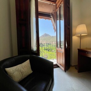 A room with a black sofa, a lamp, and a view of a mountain through an open door. - Hotel San Sebastian Hospederia (Cieza)