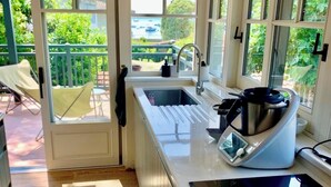 A kitchen with a built-in stove, a sink, and a window overlooking a balcony. - A0003 Newly renovated villa with pool and bay view steps from the beach (Lège-Cap-Ferret)