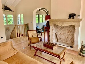 A spacious living room with a wooden floor, a fireplace with a geometric brick pattern, a chessboard, and a comfortable armchair. - A0003 Newly renovated villa with pool and bay view steps from the beach (Lège-Cap-Ferret)