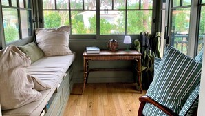 A cozy room with a built-in bench, a small table with a lamp, and a view of greenery outside. - A0003 Newly renovated villa with pool and bay view steps from the beach (Lège-Cap-Ferret)