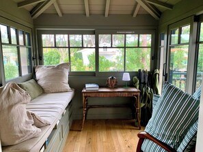 A cozy room with a built-in bench, a small table with a lamp, and a view of greenery outside. - A0003 Newly renovated villa with pool and bay view steps from the beach (Lège-Cap-Ferret)