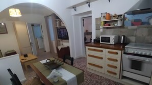 Une cuisine compacte équipée d’un four à micro-ondes, d’un four traditionnel et d’un petit coin repas avec une table et des chaises.