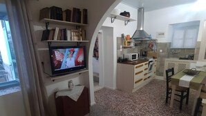 Un salon équipé d’un téléviseur, de bibliothèques, d’un coin cuisine et d’une table à manger.