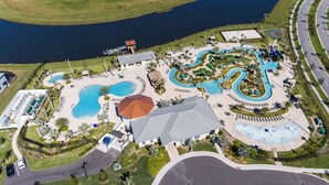 Luftaufnahme eines Resorts mit mehreren Schwimmbecken, einem großen zentralen Gebäude und einer umliegenden, angelegten Grünfläche.
