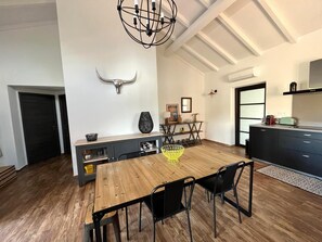 A modern kitchen with a wooden dining table, black chairs, a chandelier, and a bull head decoration on the wall. - VILLA SOUS LE PIN - 2 BDRMS - SWIMMING POOL (Zonza)
