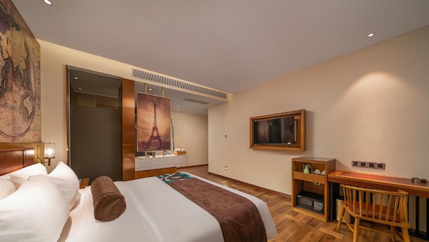 Une chambre d’hôtel avec un lit, un bureau, une chaise, une télévision et une grande carte accrochée au mur.