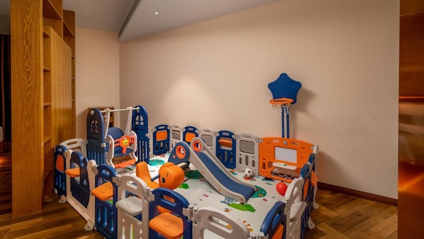 Un espace de jeux pour enfants avec un toboggan, des structures de jeu et un panier de basket.