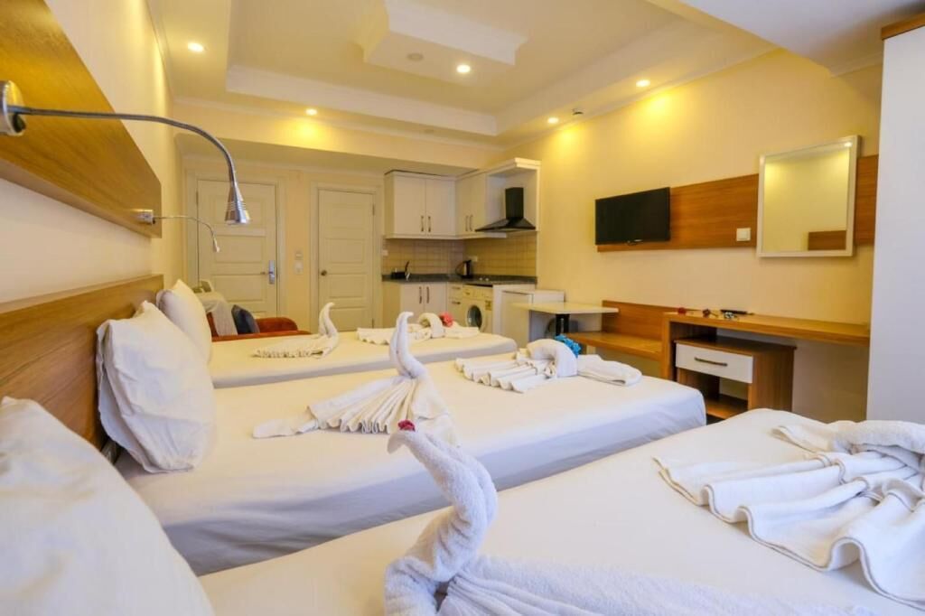 Habitación de hotel con dos camas, kitchenette, baño y televisor.