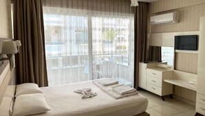 A hotel room with a bed, a desk, a TV, and a window with curtains. - Cemal Bey Hotel (Alanya)
