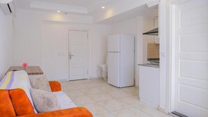 A compact living space with a kitchenette, a sofa, and a small table. - Cemal Bey Hotel (Alanya)