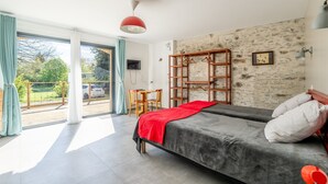 Un dormitorio con cama, escritorio, silla, armario y vistas al exterior.