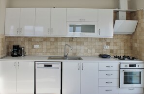 A modern kitchen with white cabinets, a built-in microwave, a gas stove, and a dishwasher. - Lacivert Apart - Sea View Apartment & Sunset Balcony & Meis Island Views (Antalya)
