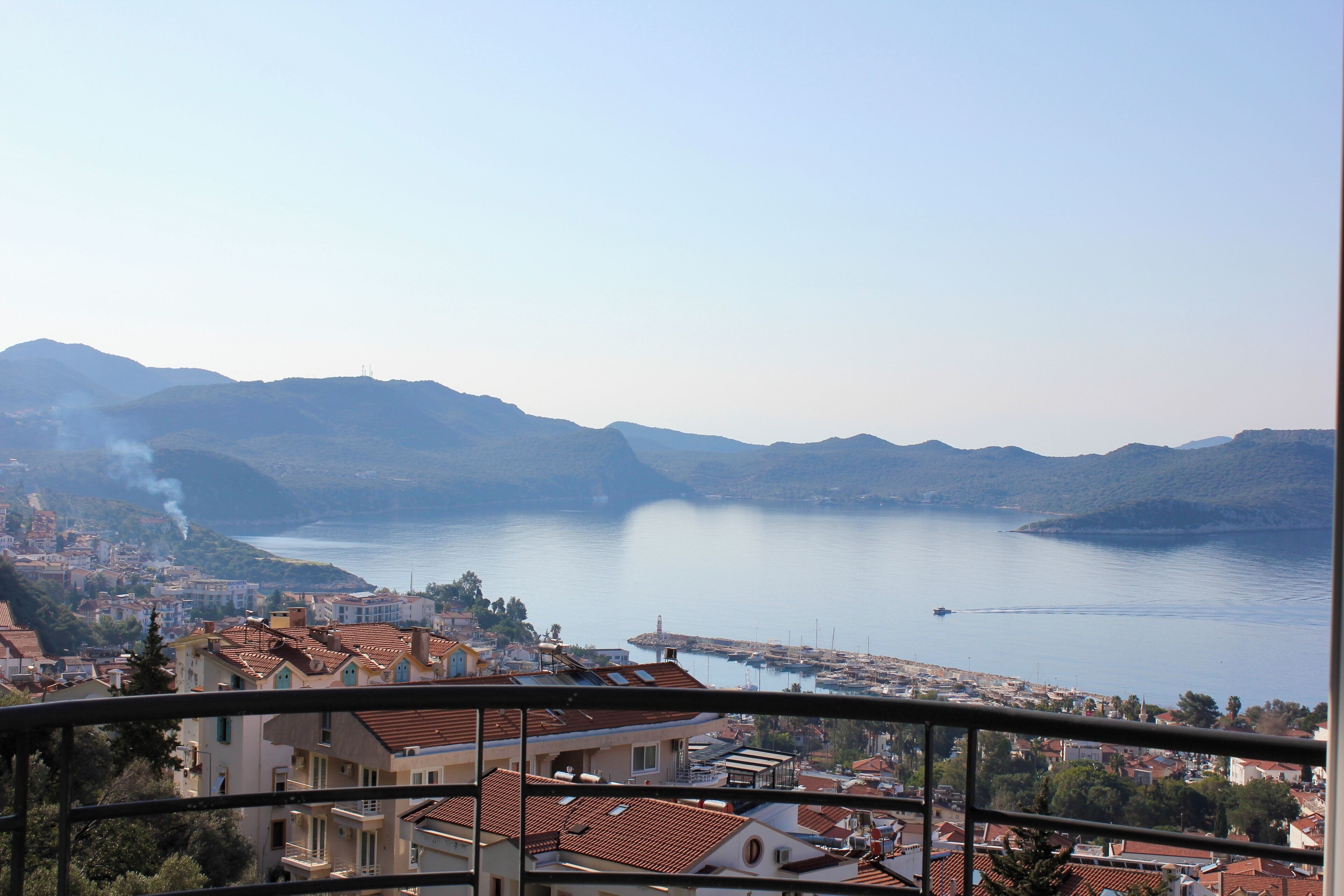 A coastal town with buildings, a marina, and mountains in the background.