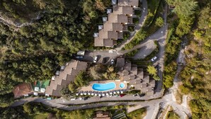 An aerial view of a residential area with multiple houses, a swimming pool, and a winding road. - Residence Oasi Bilo 1 2 Pax (Limone sul Garda)