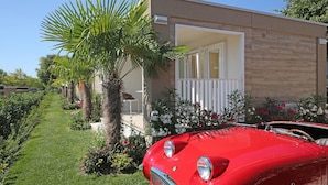 A red vintage car parked in front of a modern house with a balcony. - Residence Onda Blu Bilo BB (Manerba del Garda)
