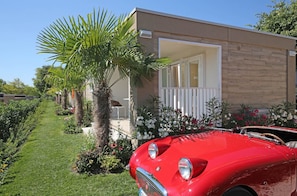Ein roter Oldtimer vor einem modernen Haus mit Balkon.