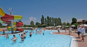 Ein Schwimmbecken mit Wasserrutsche und Sonnenschirmen.