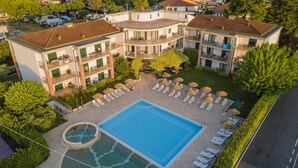 A multi-story hotel with a swimming pool, sun loungers, and a small hot tub. - Residence Nettuno Bilo (Peschiera del Garda)