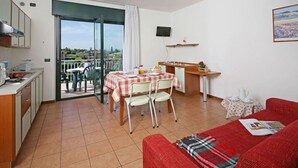 A compact living space with a kitchenette, dining area, and a balcony with a view. - Residence Nettuno Bilo (Peschiera del Garda)