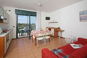 A compact living space with a kitchenette, dining area, and a balcony with a view. - Residence Nettuno Bilo (Peschiera del Garda)