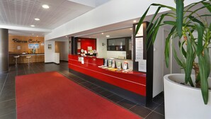 A reception area with a red counter, a large potted plant, and a 'Business Center' sign. - Les Chalets du Verdon 2p5n (Allos)