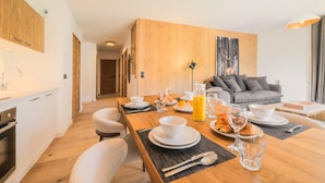 Una cocina moderna con comedor, pared de madera y sofá gris.