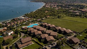Ett flygbildsbild av ett bostadsområde vid kusten med radhus, en swimmingpool och båtar på vattnet.