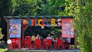 A Miniclub with red chairs and tables, surrounded by greenery. - Residence Eden Bilo 4 BB (Castelnuovo del Garda)