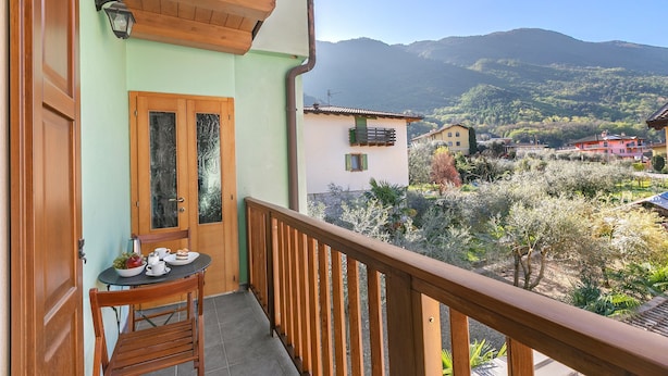 A balcony with a wooden railing, a table with a chair, and a door with glass panels. - Residenza I 3 Mori B (Arco)