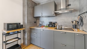 A modern kitchen with grey cabinets, a stainless steel range hood, a microwave, and a coffee maker. - Residenza I 3 Mori B (Arco)