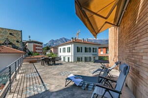 Una terrazza sul tetto con posti a sedere all'aperto, un ombrellone grande e una vista sulle montagne sullo sfondo.