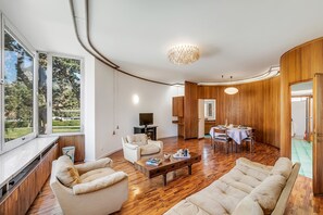 A modern living room with a sofa, armchairs, a coffee table, and a dining area with a table and chairs. - The Arco Round House (Arco)