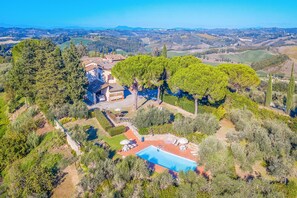 An aerial view of a villa with a swimming pool, surrounded by lush greenery and olive trees, overlooking a scenic landscape. - Amazing Chianti Site Pini Shared Pool (Castelfiorentino)