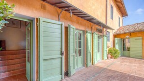 A courtyard with a paved walkway and a building with green shutters. - Villa Salivolpe Amazing Chianti View 14 (San Casciano in Val di Pesa)