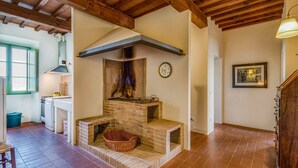 A rustic kitchen with a brick oven, wooden beams, and a dining area with a table and chairs. - Villa Salivolpe Amazing Chianti View 14 (San Casciano in Val di Pesa)