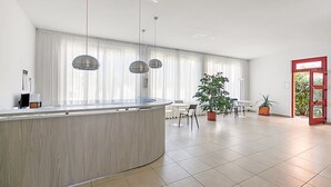 Een moderne keuken met een gebogen kookeiland, hanglampen en een eethoek met stoelen en tafels.