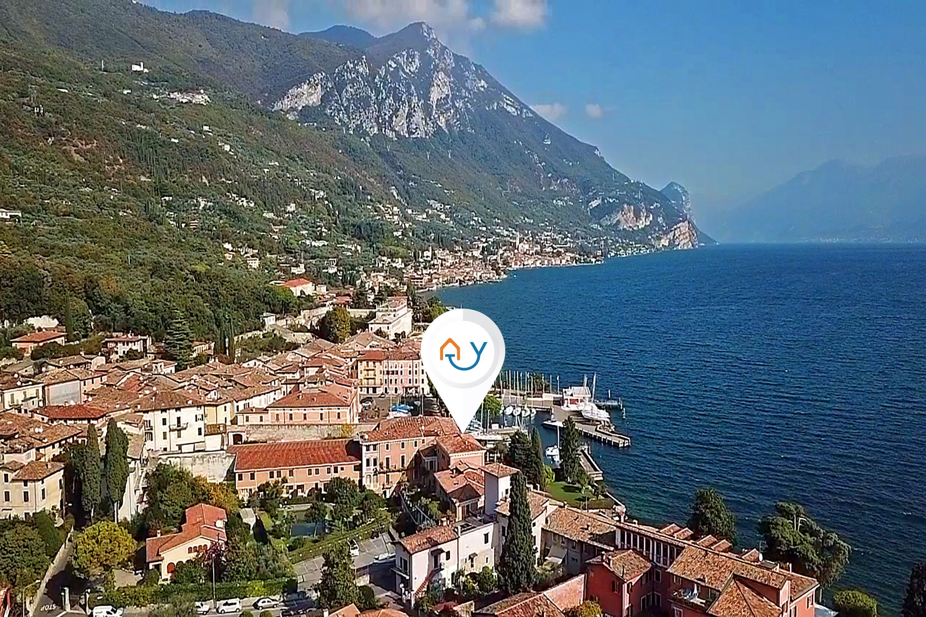 A coastal town with a marina, surrounded by mountains and a clear blue sea.