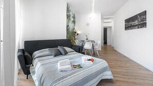 A modern hotel room with a large bed, a dining area, and a cityscape painting. - Specchio Di Cielo Arona Center (Arona)