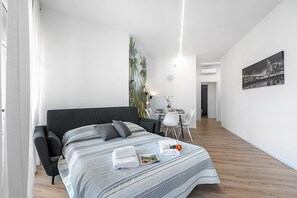 Ein modernes Hotelzimmer mit einem großen Bett, einer Essecke und einem Stadtbild.
