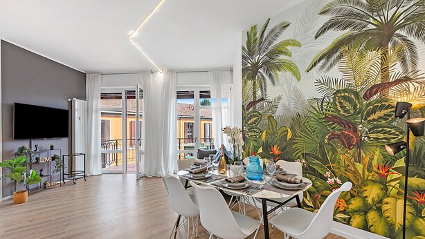 A dining area with a tropical mural, a flat-screen TV, and a view to the outside. - Specchio Di Cielo Arona Center (Arona)