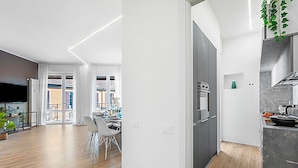 A modern kitchen with a built-in oven and a dining area with a table and chairs. - Specchio Di Cielo Arona Center (Arona)
