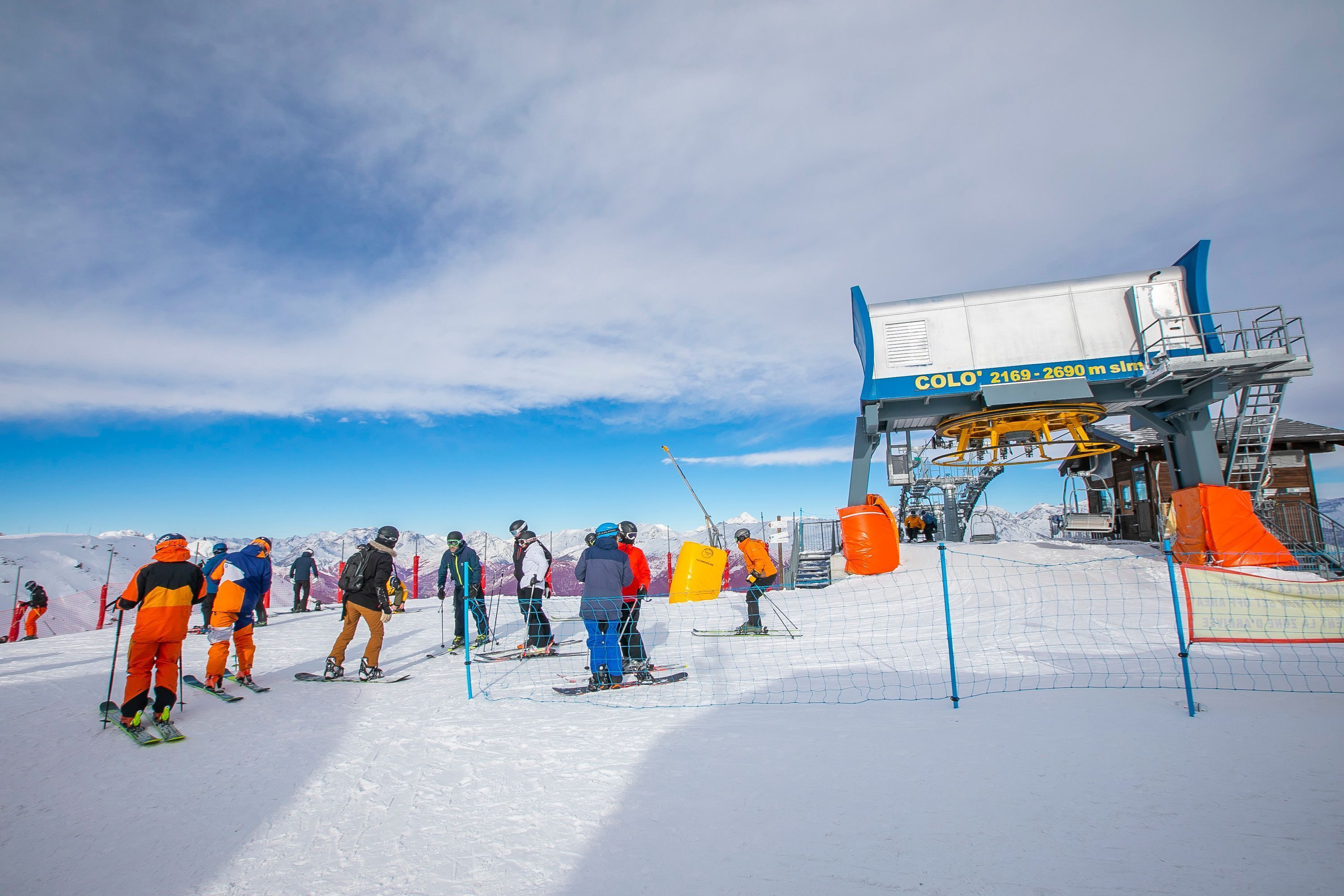 Ein Skigebiet mit Skifahrern, einer Sesselliftanlage und einem verschneiten Berggrund.