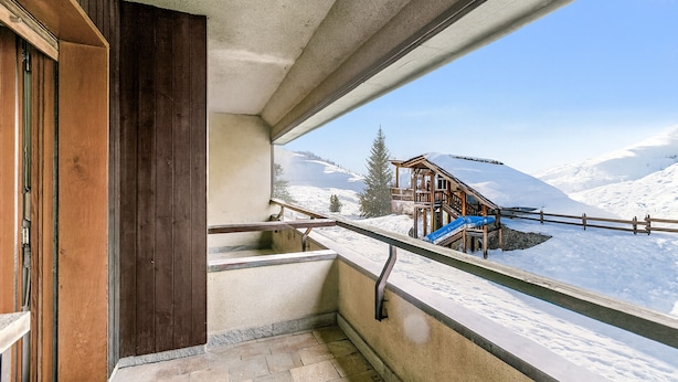 A balcony with a view of a wooden cabin and snow-covered mountains. - Prestige Eleven In The Center Of Town (Sestriere)