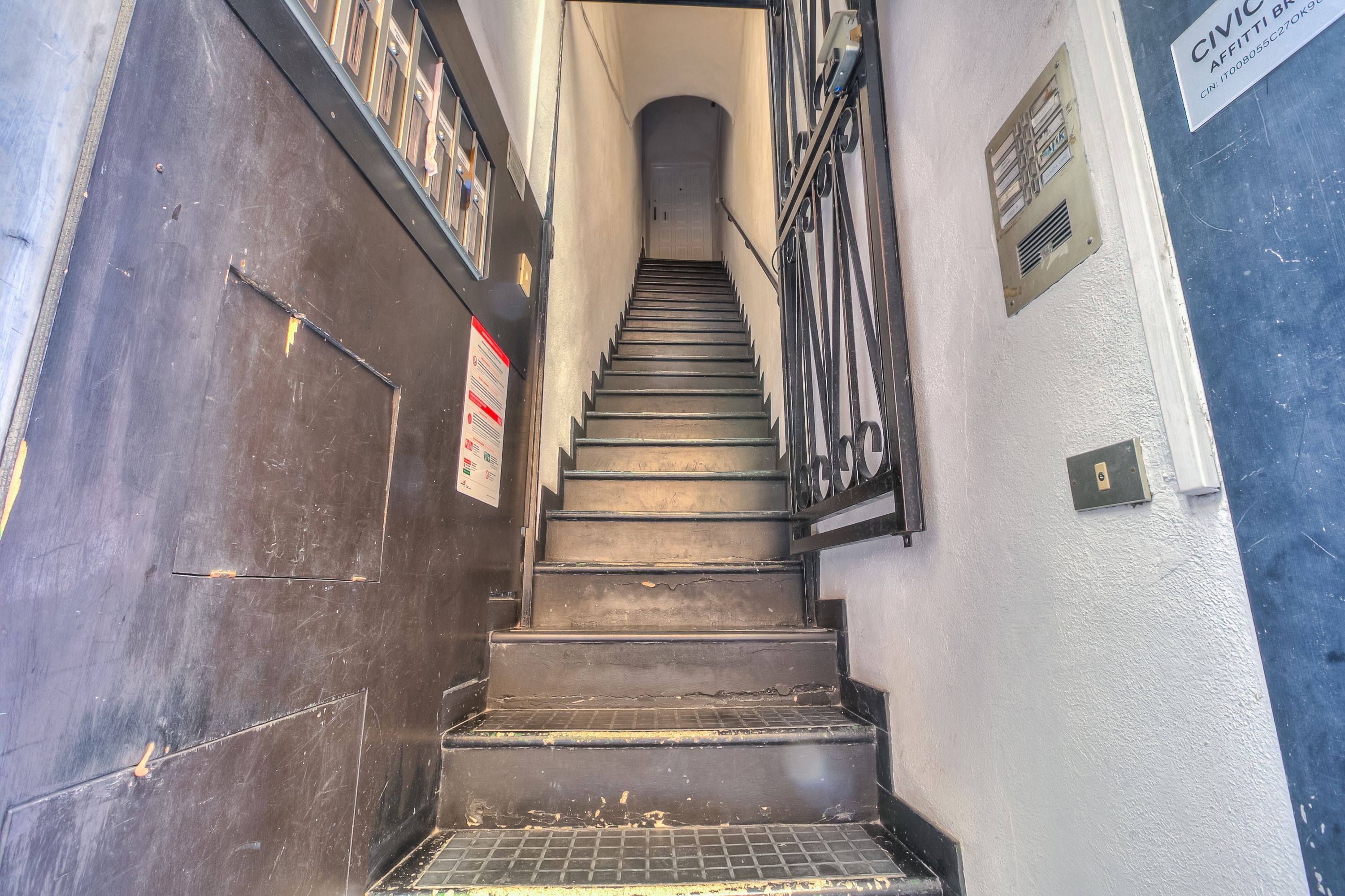 A staircase with metal railings and a door on the left.