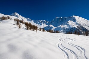Un paysage de montagne enneigé, avec un ciel dégagé et une piste de ski.
