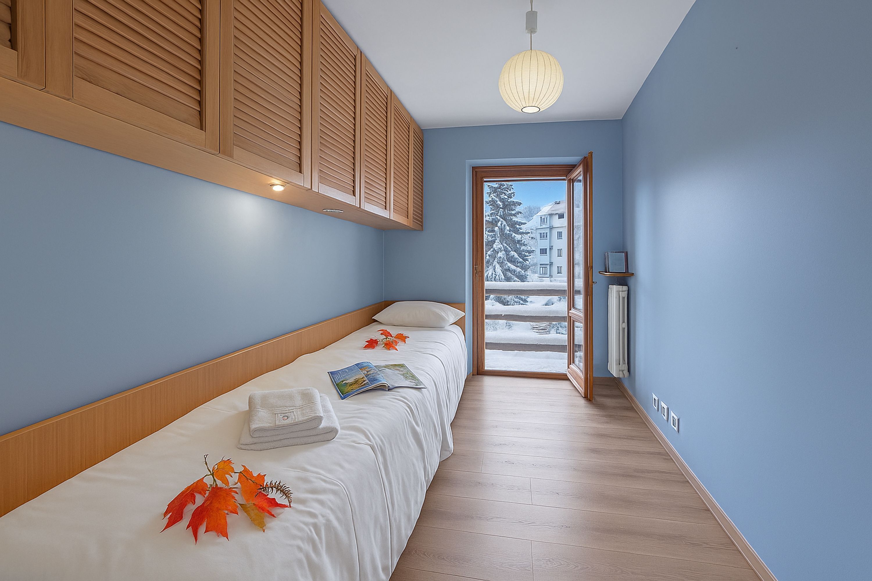 A bedroom with a bed, a window, and a view of a snowy landscape.