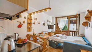 Cozinha compacta com área de refeições, uma cama e vista para um edifício pela janela.