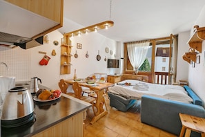 Une cuisine compacte avec un coin repas, un lit et une vue sur un immeuble par la fenêtre.