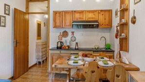 Uma cozinha compacta com armários de madeira, painel de azulejos e área de refeições com mesa e cadeiras de madeira.