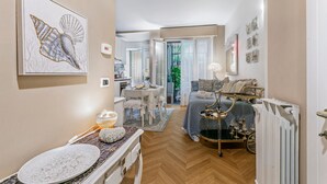 A compact living space with a dining area, a bedroom with a bed and bedside table, and a kitchen in the background. - Casa Amorosa Town Relax Alassio (Alassio)